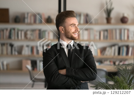Happy businessman wearing black suit standing confidently in office Happy businessman wearing black suit standing confidently in office 129212207