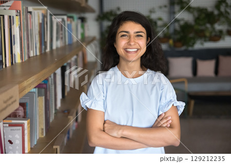 Cheerful Indian young woman standing confidently in library Cheerful Indian young woman standing confidently in library 129212235