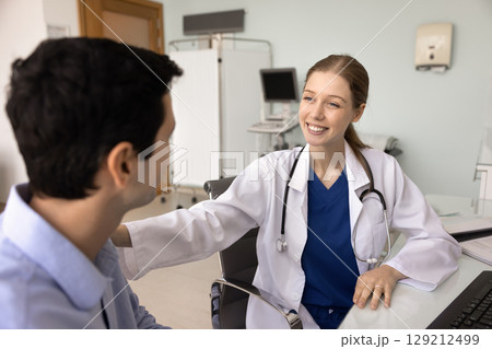 Happy young female doc touching shoulder of male patient 129212499