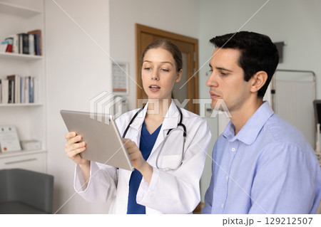 Serious young medical specialist woman explaining checkup report 129212507