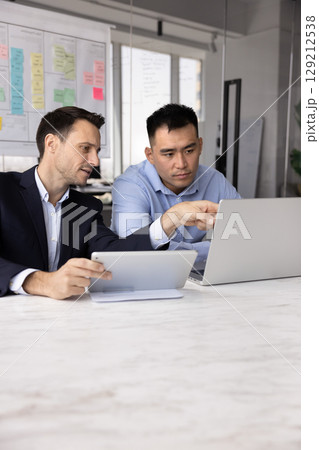 Teammates working on shared task using tablet and laptop Teammates working on shared task using tablet and laptop 129212538