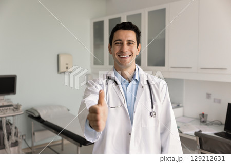 Positive handsome Hispanic general practitioner man offering handshake at camera Positive handsome Hispanic general practitioner man offering handshake at camera 129212631