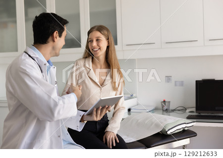 Young male Latin doctor giving handshake to young female patient Young male Latin doctor giving handshake to young female patient 129212633