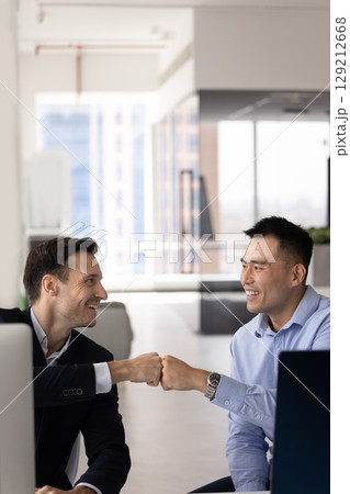Two happy multiethnic male business partners making fist bumps gesture Two happy multiethnic male business partners making fist bumps gesture 129212668