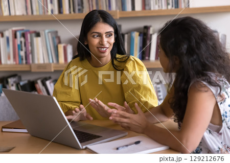 Two Indian workmates working together seated at desk with laptop 129212676