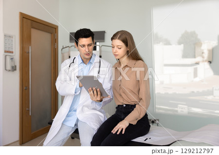 Serious young Hispanic physician man explaining medical report 129212797