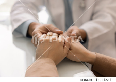 Male doctor holding hands of female patient Male doctor holding hands of female patient 129212811