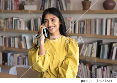Young 25s beautiful Indian woman enjoying pleasant conversation on smartphone Young 25s beautiful Indian woman enjoying pleasant conversation on smartphone 129212841