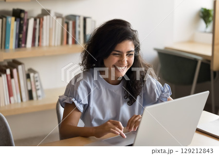 Indian woman laughing while working on laptop 129212843
