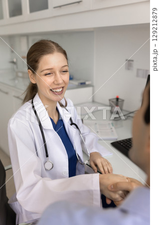 Happy young general practitioner woman shaking hands with patient 129212879