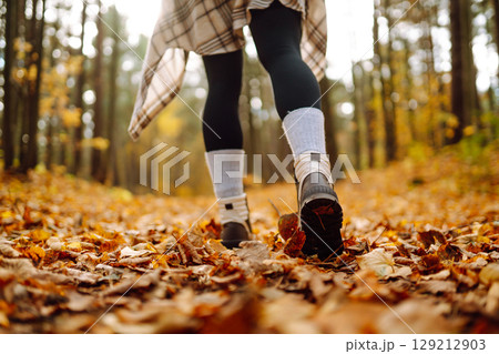 Woman's legs in boots in autumn foliage. Leaf fall. Lifestyle concept. 129212903