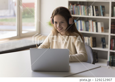 Focused female student study at distance using notebook wireless headphones Focused female student study at distance using notebook wireless headphones 129212907