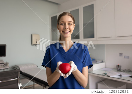Happy young ultrasound diagnosing doctor woman holding red heart Happy young ultrasound diagnosing doctor woman holding red heart 129212921