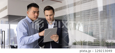 Horizontal image of two professional men working together using tablet 129213049