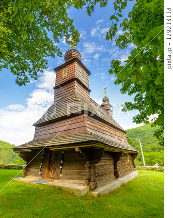 likitsary, transcarpathia, ukraine - 02 jul 2020: traditional wooden church architecture of europe. summer landscape in carpathian mountains. unique ruthenian religion heritage. front view 129213118