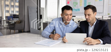 Colleagues brainstorming ideas, collaborating on file or proposal using tablet 129213121