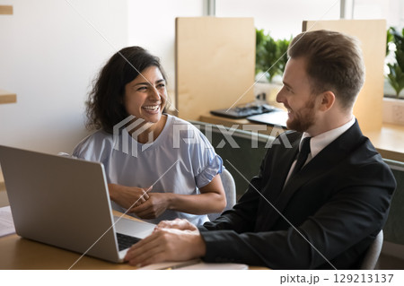 Laughing teammates engaged in friendly conversation in office Laughing teammates engaged in friendly conversation in office 129213137