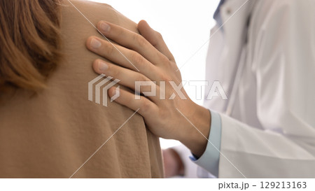 Male physician hand on shoulder of female patient 129213163