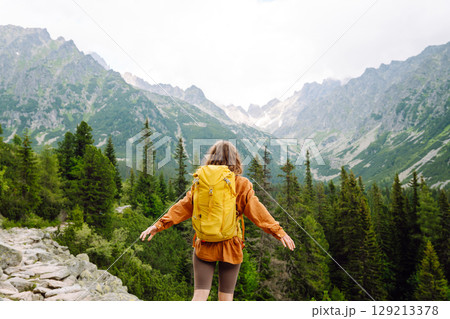 Smiling traveler with a bright backpack on a hiking mountain trail. Active lifestyle. Smiling traveler with a bright backpack on a hiking mountain trail. Active lifestyle. 129213378
