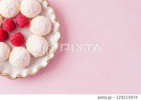 Coconut covered confections and fresh raspberries on elegant plate against pastel background, AI Generative 129213974