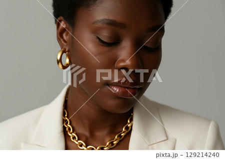 Elegant young woman in a white blazer with gold jewelry looking down, showcasing natural beauty and contemporary fashion, AI Generative 129214240