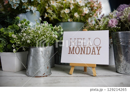 Hello Monday text on paper card with flowers decoration on wooden background Hello Monday text on paper card with flowers decoration on wooden background 129214265