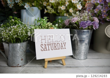 Hello Saturday text on paper card with flowers decoration on wooden background 129214283