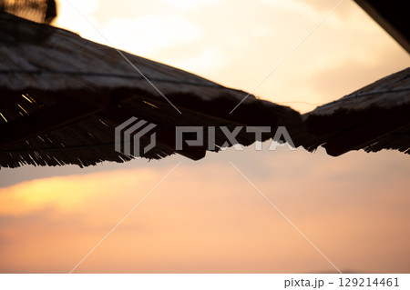 Sky with light clouds over the sea. In the foreground a bamboo sunshade. Sunset Sky with light clouds over the sea. In the foreground a bamboo sunshade. Sunset 129214461