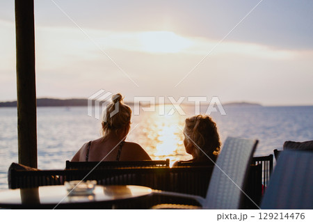 Silhouettes of two unrecognizable middle-aged ladies chatting while sitting 129214476