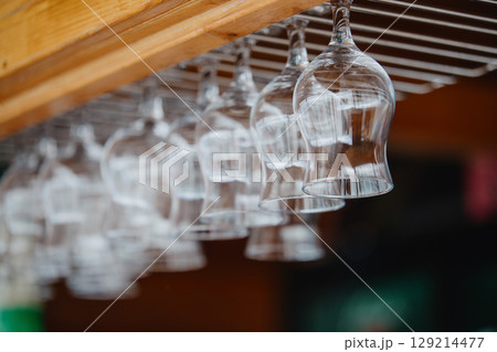 Glasses hanging upside down above the bar counter. Clean transparent glasses 129214477