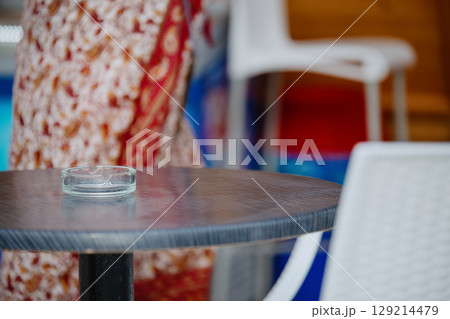 A table with a glass ashtray near a beach bar on the seashore A table with a glass ashtray near a beach bar on the seashore 129214479