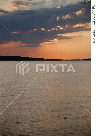 Romantic sunset and sky with calm sea with slight ripples in the background 129214499