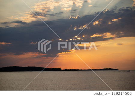 Romantic sunset and sky with calm sea with slight ripples in the background 129214500