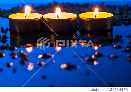 Three tealight candles burn side by side, like tiny sparks of comfort and tenderness 129214570