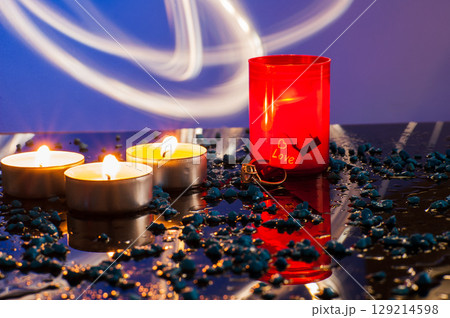 A diamond-studded gold ring is placed among burning candles that softly light the scene 129214598