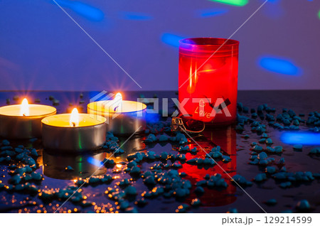 A diamond-studded gold ring is placed among burning candles that softly light the scene 129214599