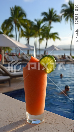 Refreshing Tropical Drink by the Poolside with Palm Trees in Background. 129214816