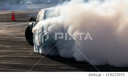 Car drifting, Blurred image diffusion race drift car with lots of smoke from burning tires on speed track, Car drifting on speed track, Professional driver drive drifting car. Car drifting, Blurred image diffusion race drift car with lots of smoke from burning tires on speed track, Car drifting on speed track, Professional driver drive drifting car. 129215031