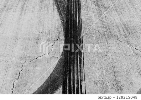 Black tire marks on road, Black rubber tire marks and tread marks, Tire trace track wheels texture and background, Auto tire tread grunge, Car wheel tyre tread track black tyre print, Aerial view. Black tire marks on road, Black rubber tire marks and tread marks, Tire trace track wheels texture and background, Auto tire tread grunge, Car wheel tyre tread track black tyre print, Aerial view. 129215049