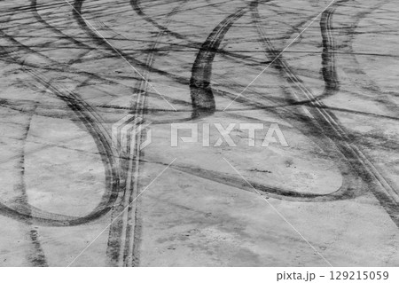 Black tire marks on road, Black rubber tire marks and tread marks, Tire trace track wheels texture and background, Auto tire tread grunge, Car wheel tyre tread track black tyre print, Aerial view. Black tire marks on road, Black rubber tire marks and tread marks, Tire trace track wheels texture and background, Auto tire tread grunge, Car wheel tyre tread track black tyre print, Aerial view. 129215059