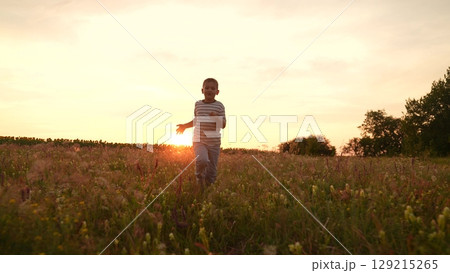 Boy running in a field at sunset, Child enjoying nature outdoors, Summer evening with golden sunlight, Happy kid playing in tall grass, Freedom and childhood memories, Peaceful countryside scene Boy running in a field at sunset, Child enjoying nature outdoors, Summer evening with golden sunlight, Happy kid playing in tall grass, Freedom and childhood memories, Peaceful countryside scene 129215265