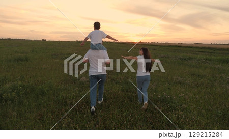 group people running green meadow field, mother father child kid son running green grass, family summer sunset, cheerful woman man playing child sunset, children dream playing airplane pilot, little 129215284