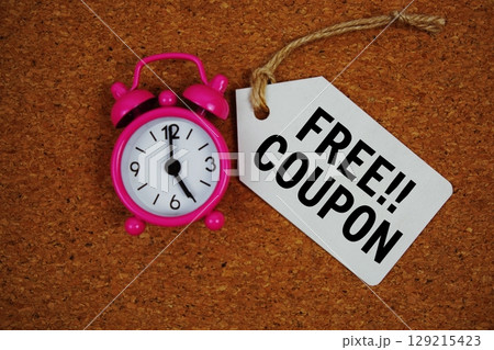 Free Coupon text on price tag with alarm clock on cork board background 129215423
