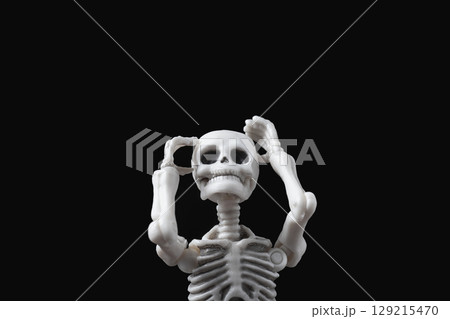 Skeleton figurine hold its head on black. Stressed and sad doll, mental problems, feeling bad, depressed, disappointment, hopeless emotions concept 129215470