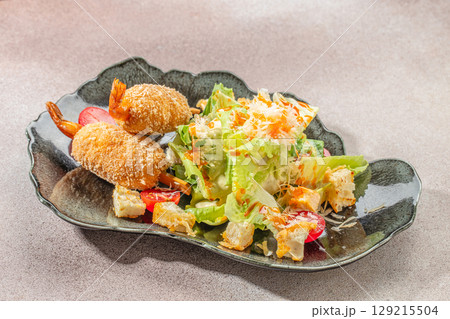 Crispy breaded shrimp served with fresh Caesar salad, croutons, cherry tomatoes, and grated cheese 129215504