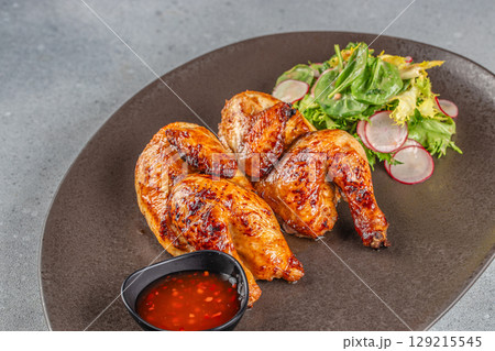 Two grilled chicken halves with radish salad and chili dipping sauce. top view. copy space 129215545