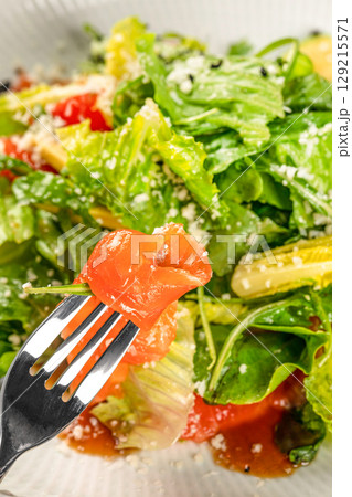 Fresh green salad with smoked salmon and cheese close-up on a fork. Fresh green salad with smoked salmon and cheese close-up on a fork. 129215571