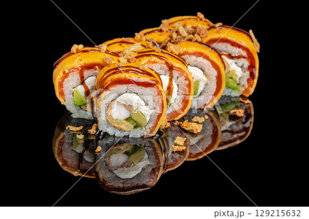 Colorful sushi rolls topped with vibrant orange sauce, cream cheese, avocado, and crispy onions on a glossy black surface Colorful sushi rolls topped with vibrant orange sauce, cream cheese, avocado, and crispy onions on a glossy black surface 129215632