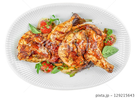 Grilled chicken quarters glazed with savory herbs and sauce, served with cherry tomatoes and fresh basil on a white plate isolated on white background. top view 129215643