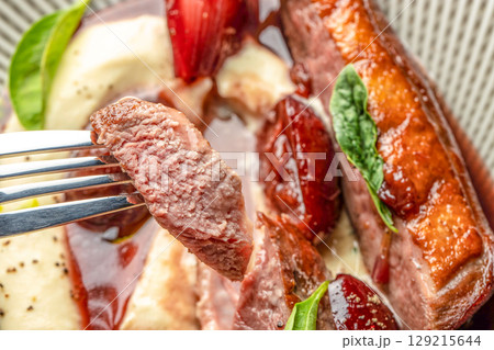 Medium-rare duck breast served with red wine reduction, roasted plums, and creamy mashed potatoes top view 129215644